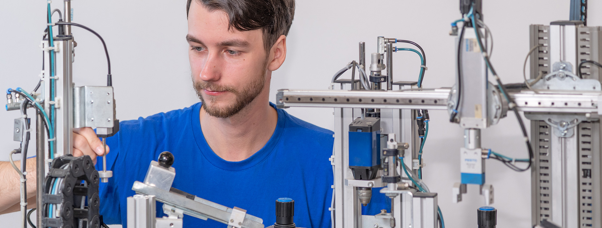 Worker in a blue shirt operating and inspecting industrial automation equipment