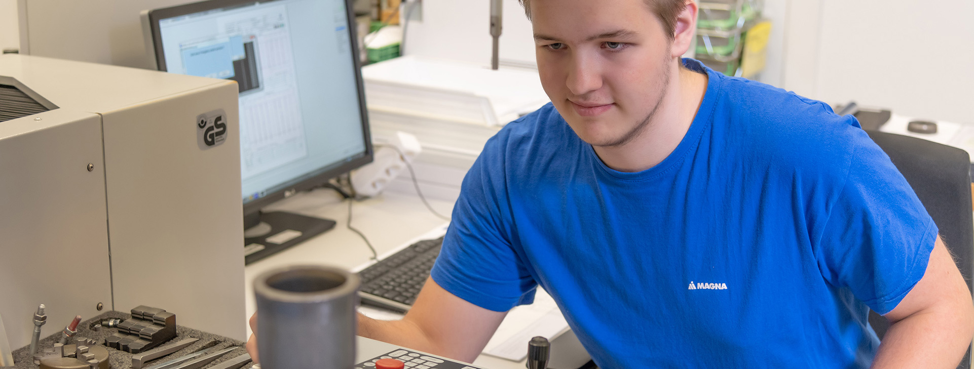 Worker analyzing a metal part using a testing machine and computer software