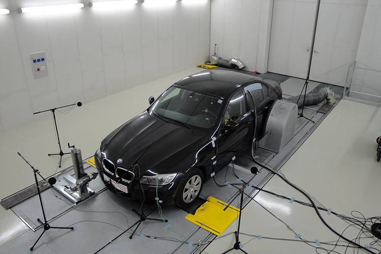 Black vehicle in a test chamber hooked up to a 4WD Chassis Dynamometer