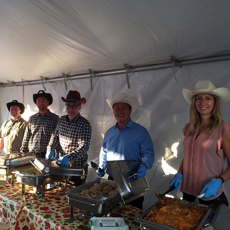 Adriana Huntington and coworkers wearing cowboy hats and serving food at a company picnic