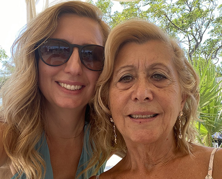 Adriana Huntington and her mother smiling with palm trees in the background