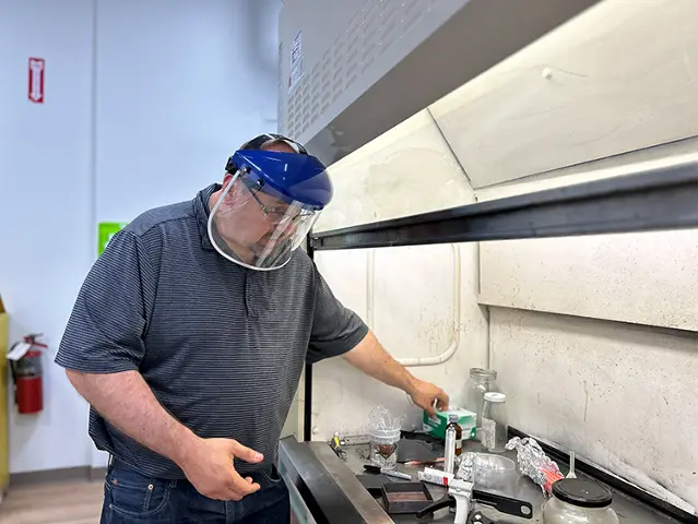 Team member working with safety gear under a fume hood