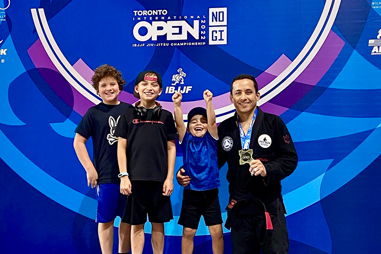Four people celebrating after being presented with a medal for winning a Jiu-Jitsu match