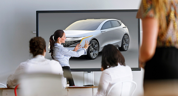 People in a meeting room and looking a vehicle on a screen and discussing design