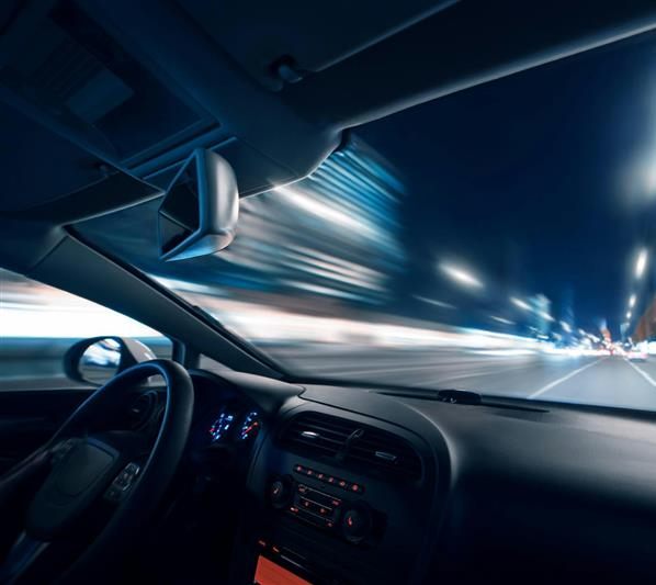 Interior view of a car with Driver Monitoring System in the interior mirror speeding through a blur of city lights at night. "Tech Talk" is boldly displayed, suggesting a modern, dynamic theme.